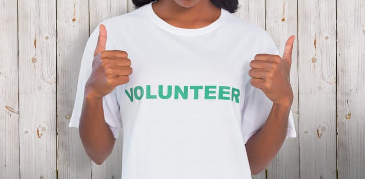 Woman wearing volunteer tshirt and giving thumbs up against wooden background
