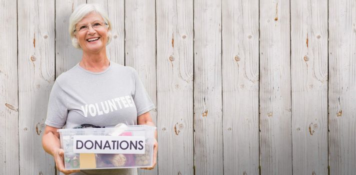 Happy grandmother holding donation box against wooden background