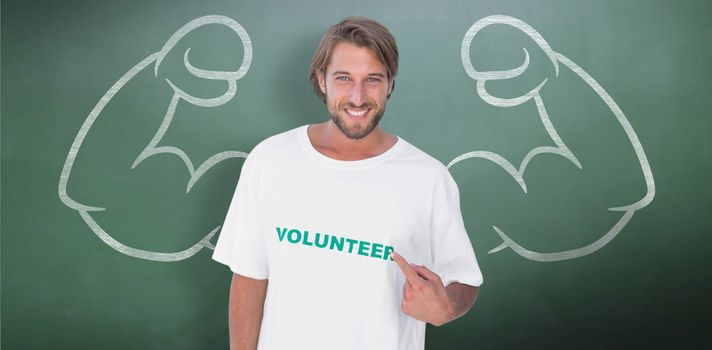 Smiling man pointing to his volunteer tshirt against green chalkboard