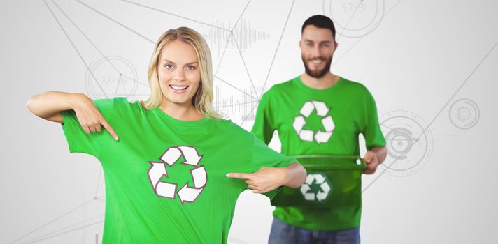 Portrait of woman pointing towards recycling symbol on tshirts  against interface with graphs