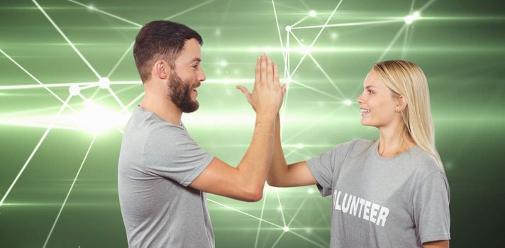 Smiling volunteer doing high five in office against glowing geometric design