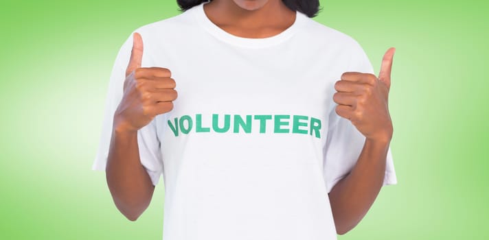 Woman wearing volunteer tshirt and giving thumbs up against green vignette