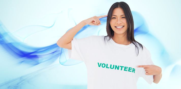 Smiling woman pointing to her volunteer tshirt against blue abstract design