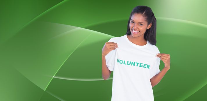Young woman wearing volunteer tshirt and pointing to it against abstract green design