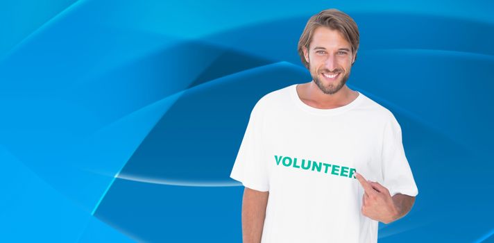 Smiling man pointing to his volunteer tshirt against abstract blue design