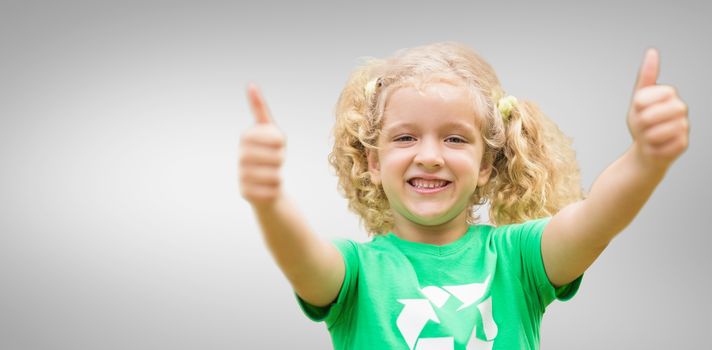 Happy little girl in green with thumbs up  against grey vignette