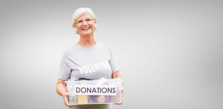 Happy grandmother holding donation box against grey vignette