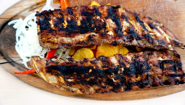 spare ribs in wooden tray with vegetables and potato