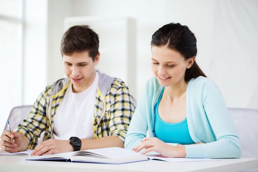 education and school concept - two smiling students with textbooks and books at school