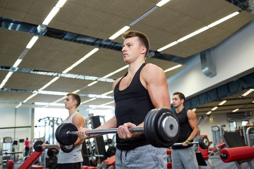 sport, bodybuilding, lifestyle and people concept - group of men with barbell flexing muscles in gym