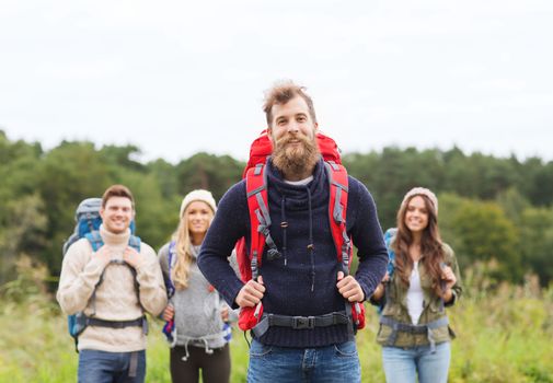 adventure, travel, tourism, hike and people concept - group of smiling friends standing with backpacks