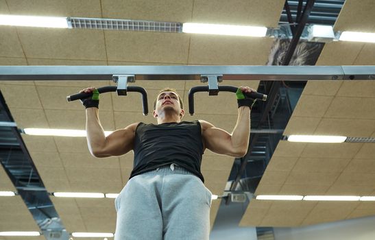 sport, fitness, lifestyle and people concept - young man doing pull-ups in gym