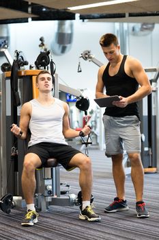 sport, fitness, equipment, lifestyle and people concept - man exercising on gym machine