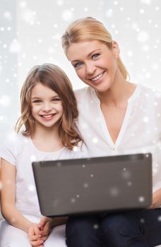 family, child, technology and home concept - smiling mother and little girl with laptop at home