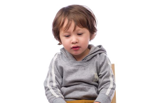 A cute 3 year old boy with a sad expression on a white background.