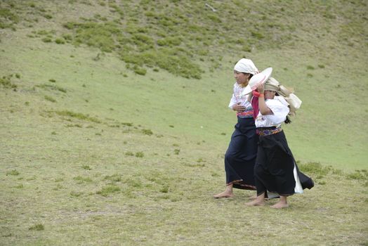 Cochasqui, Ecuador, - June, 2013. Two American Indians in traditional Ecuadorian costumes are having a rest between the participation in Solstice holiday. Their dancing is an important  part of the whole performance, in which shamans from different tribes of Latin America are participating.