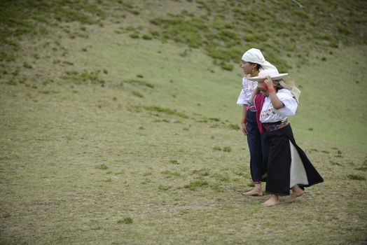 Cochasqui, Ecuador, - June, 2013. Two American Indians in traditional Ecuadorian costumes are having a rest between the participation in Solstice holiday. Their dancing is an important  part of the whole performance, in which shamans from different tribes of Latin America are participating.