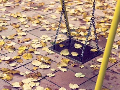 Empty swing with leaves in the autumn season