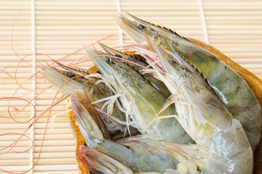 raw shrimps in cup on wooden mat.