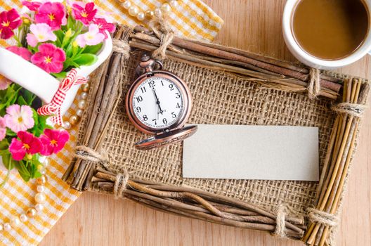Vintage paper blank tag and clock with fram and flower on wooden background.