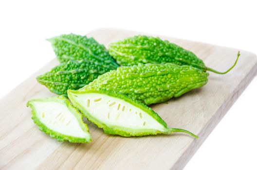 Momordica charantia, Bitter melon,Bitter Gourd, Carilla Fruit, Balsam Apple, Balsam Pear or Bitter Cucumber on chopping block with white background