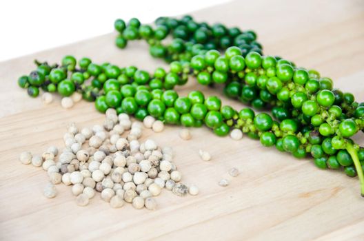 white pepper seeds and branch fresh green peppers on wooden background.