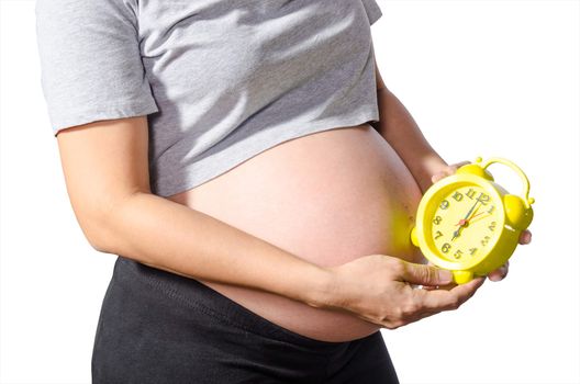Belly of a pregnant woman with alarm clock. Isolated on white background, clipping path.