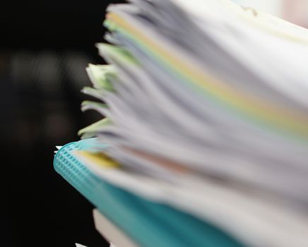 Pile of documents and blue file on desk at office.