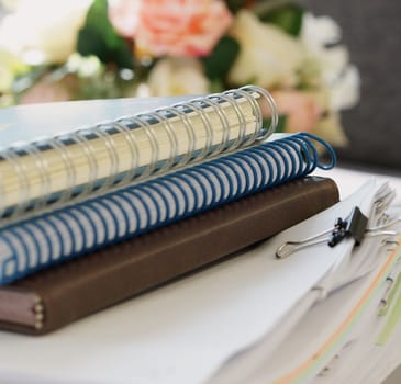 Three notebooks and stack of document placed on desk at office.