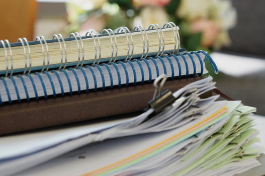 Three notebooks and stack of document placed on table at office.