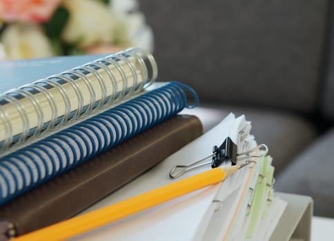 Three notebooks, yellow pencil and stack of document placed on desk at office.