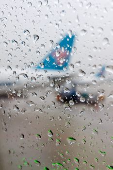 Water drops on an aircraft window with airplanes on a background