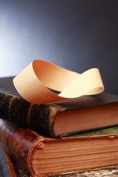 Paper Mobius strip on old books against dark background