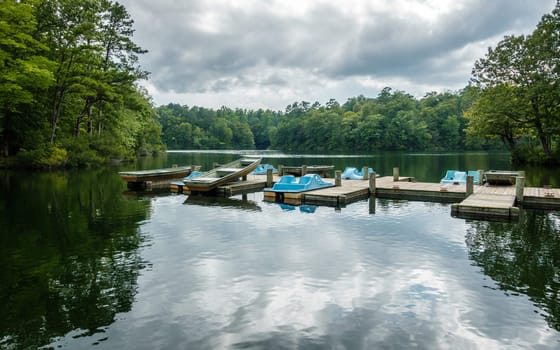 Aluminium bass fishing boat and pedalos at wooden dock in Virginia, America USA
