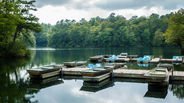 Aluminium bass fishing boat and pedalos at wooden dock in Virginia, America USA