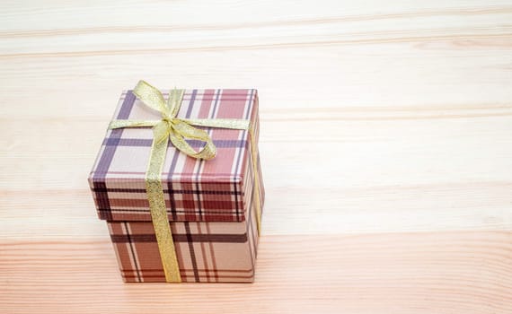 brown gift box with bow on wooden table