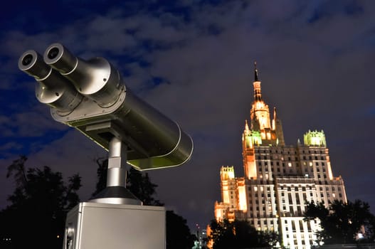 observation telescope at a dark sky looks at a tall building