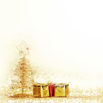 Decorative golden toy christmas tree and gifts on golden background