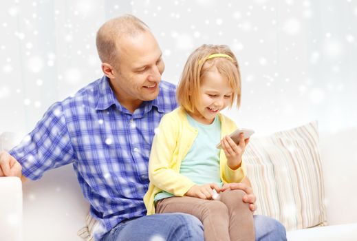 family, childhood, parenthood, technology and people concept - happy father and daughter with smartphone at home