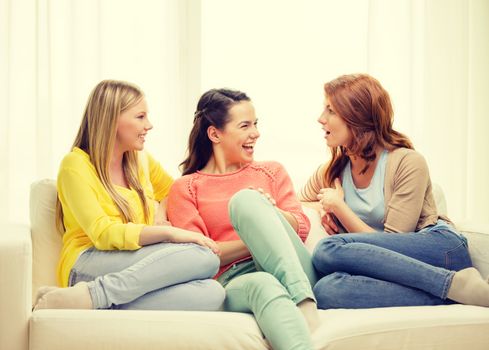 friendship and happiness concept - three girlfriends having a talk at home