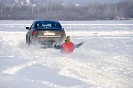 the car carrying the man on ice-boat  in tow in the snow
