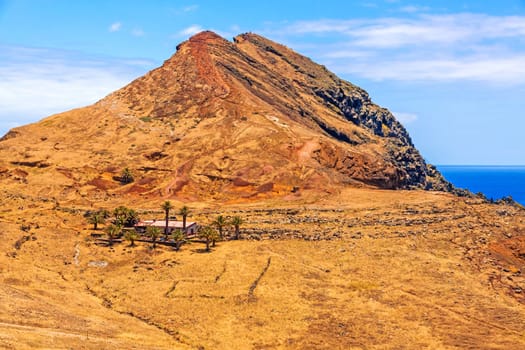 Ranch-like house / building in dry desert landscape with palms and mountain in the background