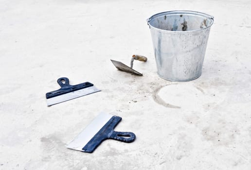 metal bucket with cement and spatulas