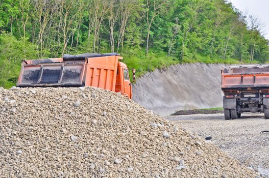 pile of gravel and dump trucks