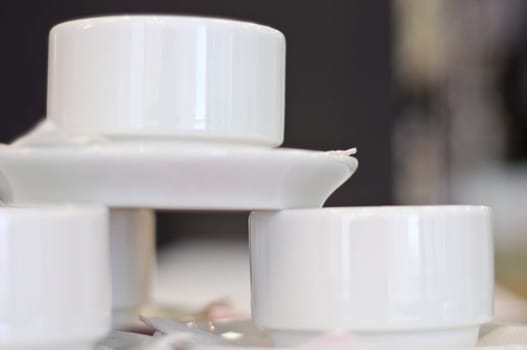 three white porcelain tea cups and saucers and napkins close up