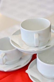 three white porcelain tea cups and saucers and napkins