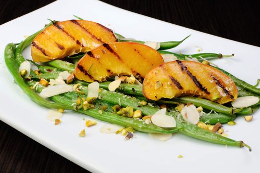 Salad of green beans , peaches, almonds, pistachios and sprinkled with Parmesan