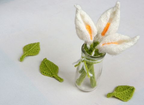 Romantic desk with ornament from handmade product, lily flower knit from white yarn, handbook, knitting pencil, coffee cup, glasses, beautifil craft