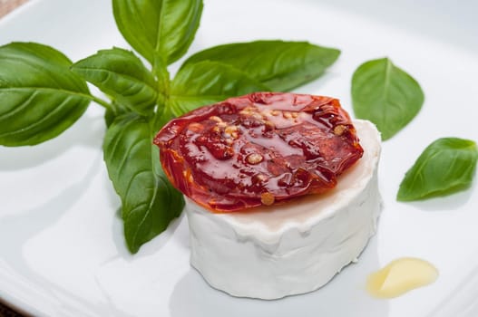 Appetizer of goat cheese with dried tomatoes and basil