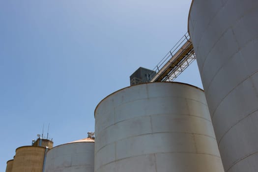 Large steel grain silos with cloudless blue skies.